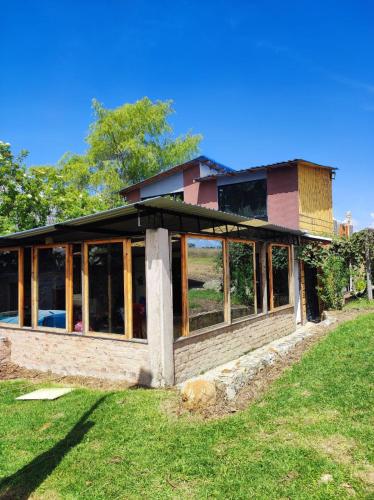 a house being constructed with glass windows on a field at Finca Buenos aires in Oicatá