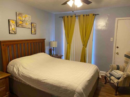 ein Schlafzimmer mit einem Bett und einem Stuhl sowie gelben Vorhängen in der Unterkunft Midtown Memphis- free ride to down town in Memphis