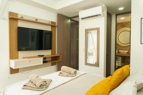 een slaapkamer met een tv en een bed met handdoeken bij Pet-Friendly Pool Retreat with Luxury Hot Showers in Santa Marta