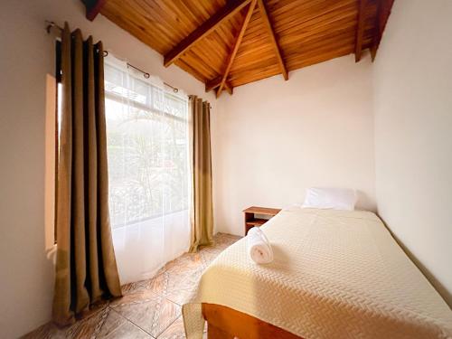 um quarto com uma cama e uma grande janela em Edén Guest House em Monteverde