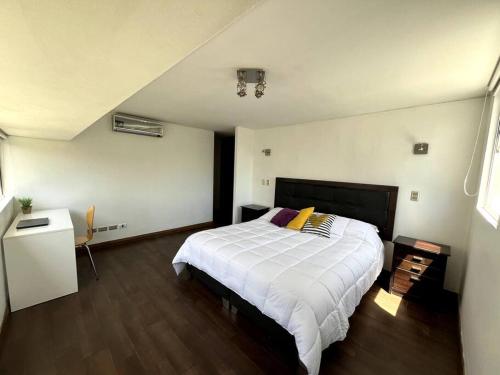 1 dormitorio con 1 cama blanca grande y suelo de madera en A pasos del Costanera Center! en Santiago