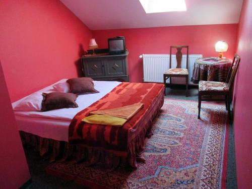 1 dormitorio rojo con 1 cama y 1 silla en Gościniec pod Kłosem en Kłos