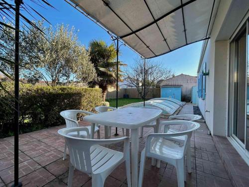 une table blanche et des chaises sur une terrasse dans l'établissement Maison Oléron avec piscine privée, 6 couchages, proche centre et parc aquatique - FR-1-246A-158, à Dolus-d'Oléron