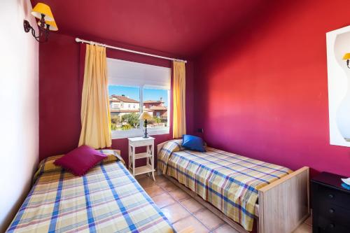 2 camas en una habitación con paredes rojas y ventana en Fabuloso ROMANI entre mar y montañas, en Bonmont Terres Noves