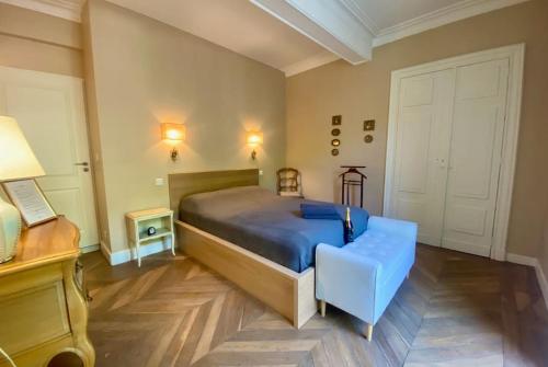 une chambre avec un lit et une chaise bleue dans l'établissement L'historien - avec balcon coeur de Nîmes, à Nîmes