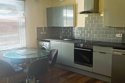 een keuken met een tafel, een wastafel en een fornuis bij Gravesend 1 Bedroom Flat 2 Min Walk to Station & Town Centre in Kent