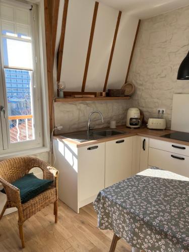 une cuisine avec un évier et une table avec une chaise dans l'établissement La Genette, à La Rochelle