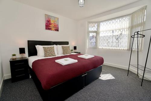 a bedroom with a large bed with a red blanket at Serene 3Bed Escape - Fully Furnished Holiday Haven in Coventry