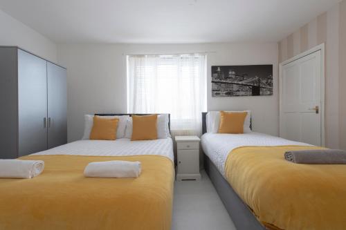 3 Bed House in Rochester 4 beds sleeps 7 في Wainscot: سريرين في غرفة صفراء وبيضاء