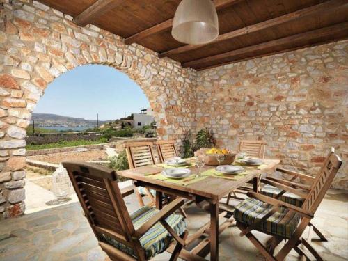 a wooden table and chairs on a patio with a stone wall at Villa Hermes - Luxury Villa Paros in Kampos Paros