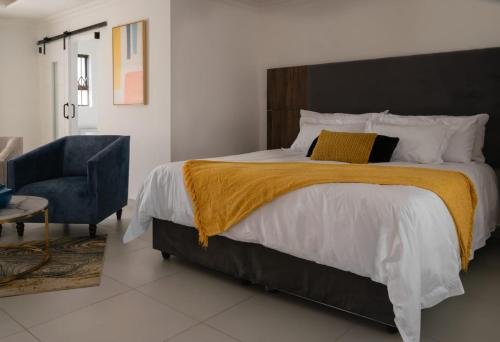 a bedroom with a large bed and a chair at Hotel El Infinito in Kempton Park