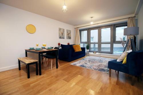 a living room with a table and a blue couch at Hamilton Court Apartment for 4 Guests, Bright and Central Location with Balcony and Wi-Fi in Bristol