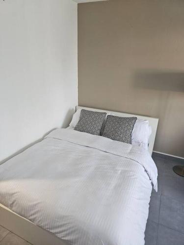 ein weißes Bett mit zwei Kissen darüber in der Unterkunft Le Vénitien in Montreuil