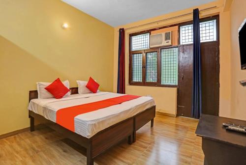 a bedroom with a bed with red pillows on it at Prince Residency in Greater Noida