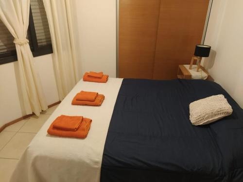 1 dormitorio con 1 cama con 2 toallas de color naranja en Departamento Amoblado Nva Cba en Córdoba