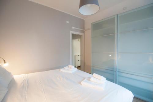 a bedroom with a white bed and a glass shower at Blanco Apartment - AmbrogioHost in Bologna