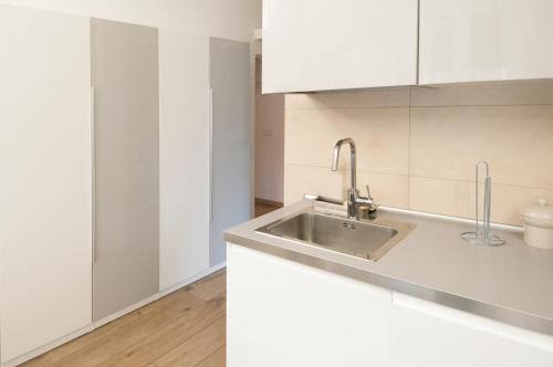 una cucina con lavandino e armadietti bianchi di Blanco Apartment - AmbrogioHost a Bologna