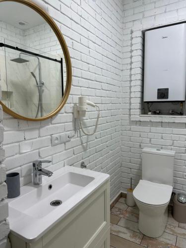 a white bathroom with a sink and a mirror at Sinay Hotel & Restaurant in Chechel'nyk