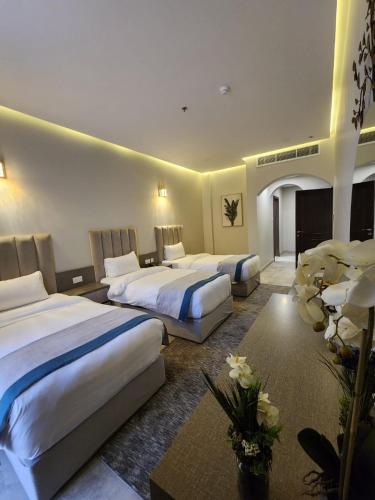 a hotel room with three beds and flowers at Eliana Hotel in Al Khobar