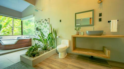 a bathroom with a sink and a toilet and a tub at Eden Organic Farm & Bungalows in Fortuna