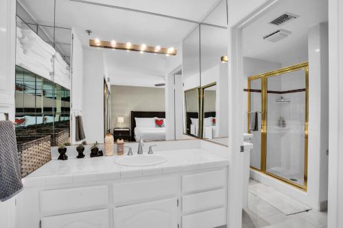 a white bathroom with a sink and a mirror at Keith Haring Inspired 2BD Deauville Condo - A Ryson Property in Palm Springs