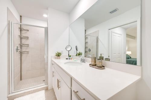 a white bathroom with a sink and a shower at Breezy Ave Maria Condo with Golf Course On-Site! in Harker