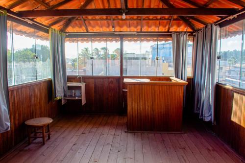 a large room with wooden floors and windows and a counter at Pousada Mirante do Sol in Piúma
