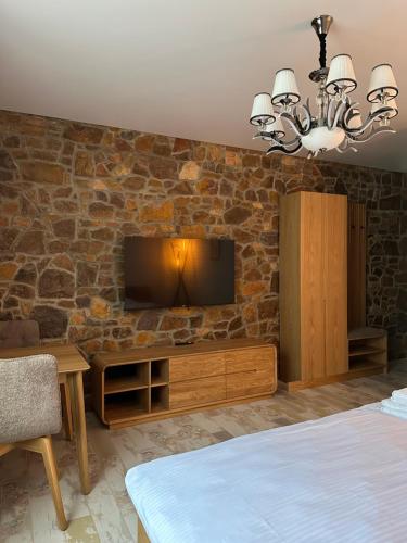 a bedroom with a stone wall with a flat screen tv at Sinay Hotel & Restaurant in Chechel'nyk
