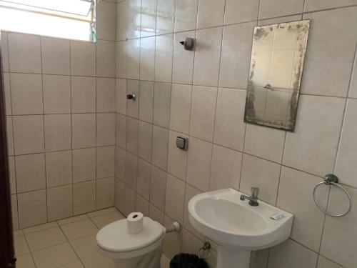 a bathroom with a sink and a toilet and a mirror at Hotel Vila de São Vicente in São Vicente