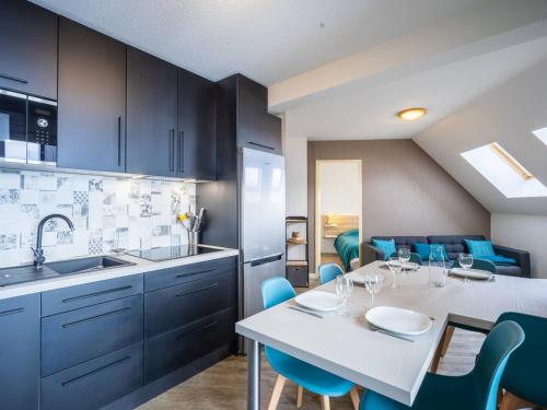 une cuisine avec une table blanche et des chaises bleues dans l'établissement Duplex rénové 6 pers, balcon, casier à skis, parking gratuit - FR-1-695-20, à Germ