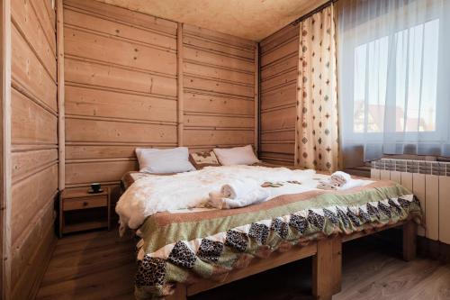 a bedroom with a large bed with a wooden wall at Grota zbójnicka apartament i pokoje in Gliczarów