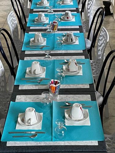 una mesa larga con placas azules y sombreros. en Europe Hotel, en Beaurepaire-en-Bresse