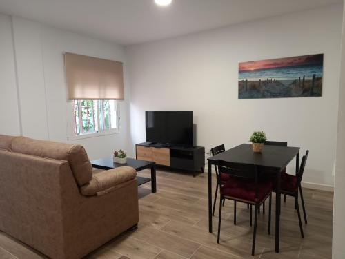 sala de estar con sofá, mesa y TV en Apartamento Ramírez, en Conil de la Frontera