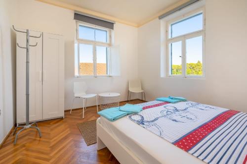 a bedroom with a bed and two windows at Authentic house in Dubrovnik