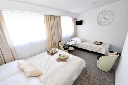 a hotel room with two beds and a clock on the wall at Villa Sovita in Łeba