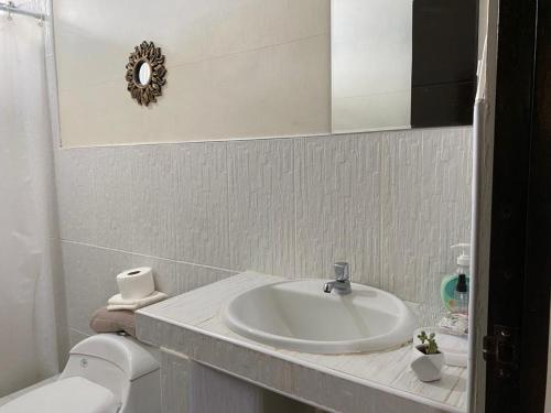 uma casa de banho com um lavatório, um WC e um espelho. em CASA GRAU - ZORRITOS em Caleta Grau