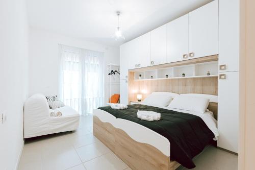 a white bedroom with a large bed and a white chair at Casa Rosolino - A due passi dal Campus Biomedico - Roma Trigoria in Rome