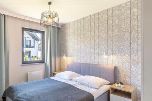 a bedroom with a blue bed and a window at Apartament w Nautikka Resort Krynica Morska in Krynica Morska