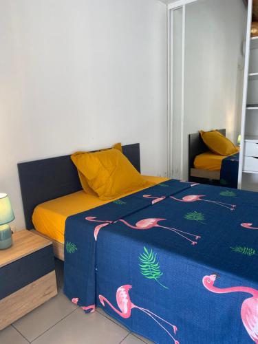 - une chambre dotée d'un lit avec une couverture bleue et des flamants roses dans l'établissement Villa marigua 2, à Les Abymes