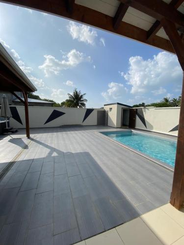 uitzicht op een zwembad vanaf de patio van een huis bij Villa marigua 2 in Les Abymes