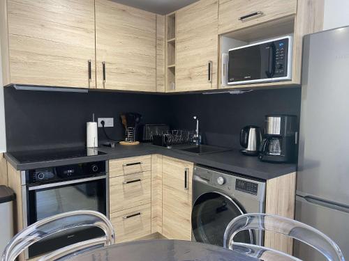 La cuisine est équipée de placards en bois, d'un four micro-ondes et d'un lave-vaisselle. dans l'établissement Appartement T2 rénové avec climatisation et internet, proche centre et étang de Thau - FR-1-553-193, à Balaruc-les-Bains