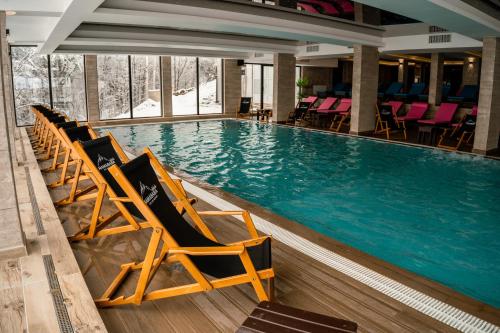 a large swimming pool with chairs in a hotel at Mamababa FREE SPA & Wellness Kopaonik in Kopaonik