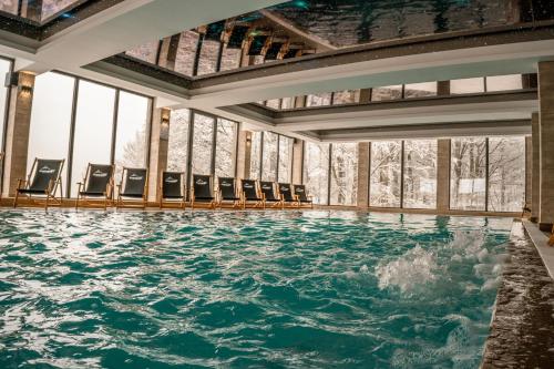 a pool of water in a room with chairs at Mamababa FREE SPA & Wellness Kopaonik in Kopaonik