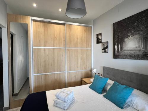 1 dormitorio con 1 cama grande con almohadas azules en Espectacular apartamento junto al mar, con piscina en Málaga, en Málaga