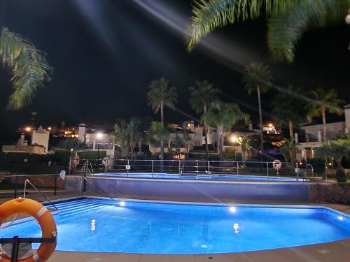 una piscina notturna con palme e un salvagente di Sun & Palms - cozy flat in quiet neighbourhood with a great pool area a Málaga