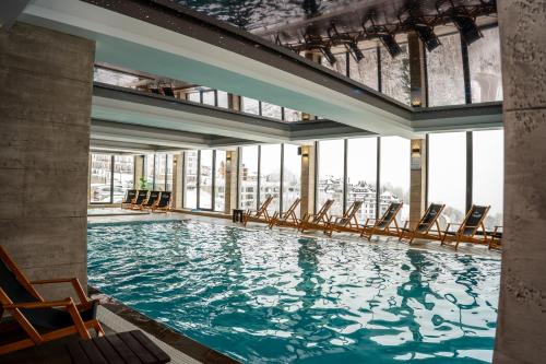 a large swimming pool with chairs in a building at Mamababa FREE SPA & Wellness Kopaonik in Kopaonik