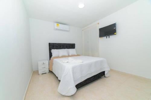 a white bedroom with a bed and a tv at Chic 2Bedroom in Cúcuta in Villa del Rosario