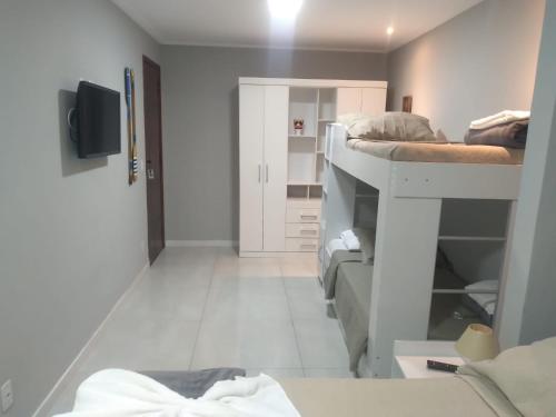 a room with two bunk beds and a tv at Pousada Canoa dos Anjos suítes in Arraial do Cabo