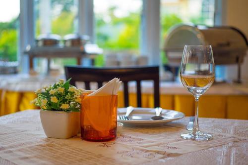 a table with a glass of wine and a plant at Excella Hotel in Ubon Ratchathani