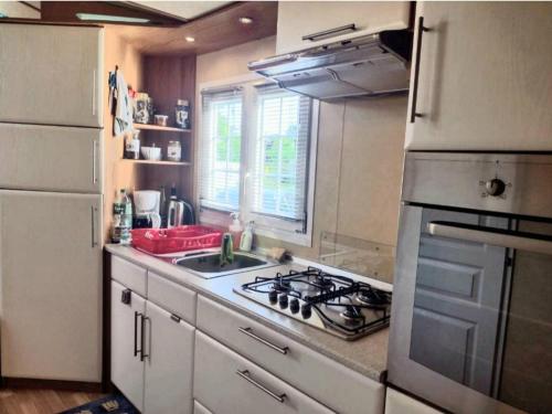 a kitchen with a sink and a stove top oven at Mobil home avec terrasse 4 personnes in Ambon